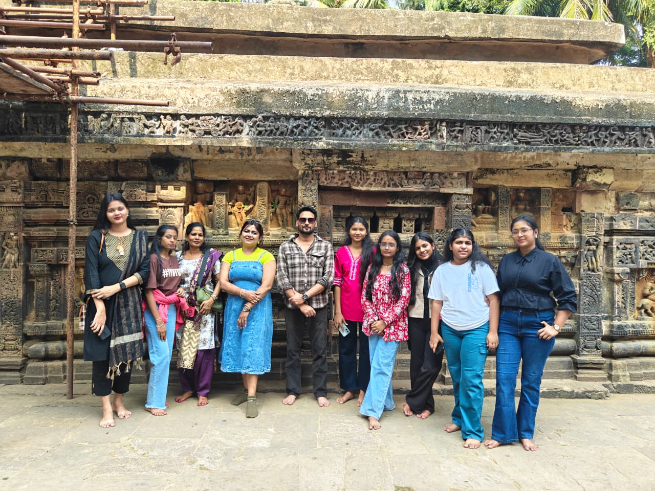 Group of students posing in front of an ancient carved temple wall during outing