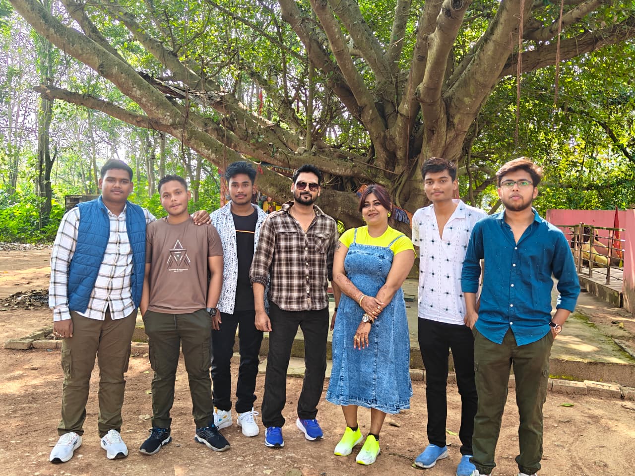 Students and teachers taking a group photo under a massive banyan tree shade